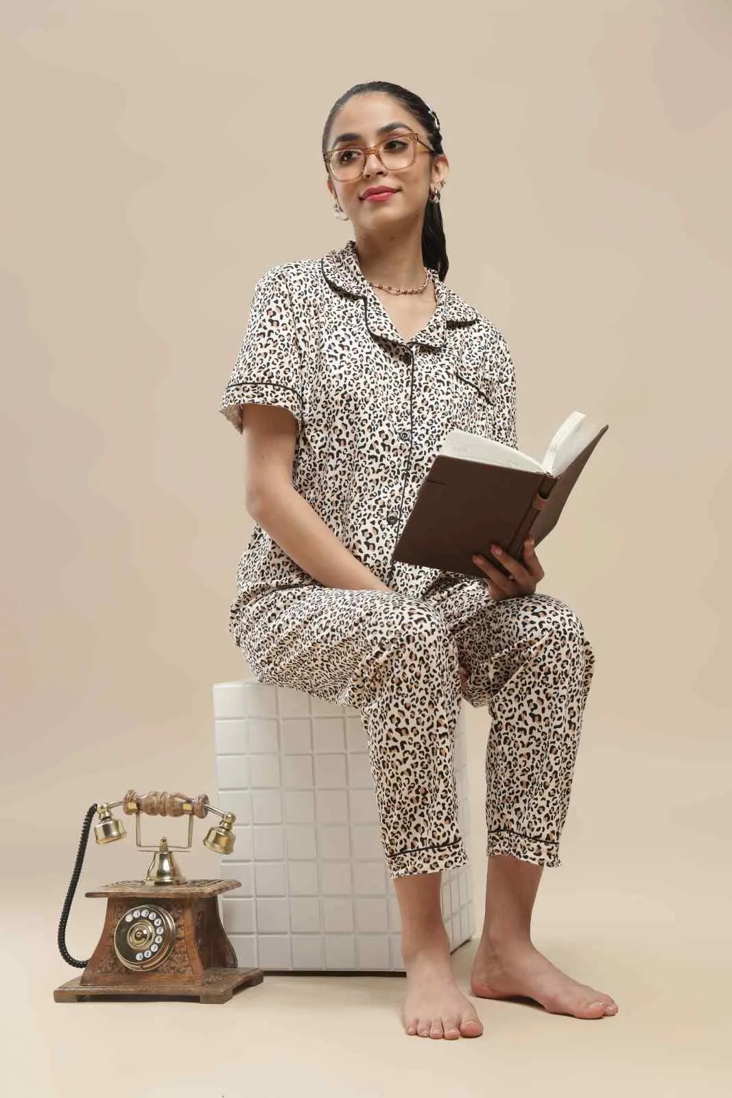 a full-length lifestyle view of the koozy leopard print pj set for women, styled against a neutral beige backdrop. this pinterest-inspired, breathable cotton set is designed for a softly structured yet incredibly cozy morning look, perfect for animal print lovers.