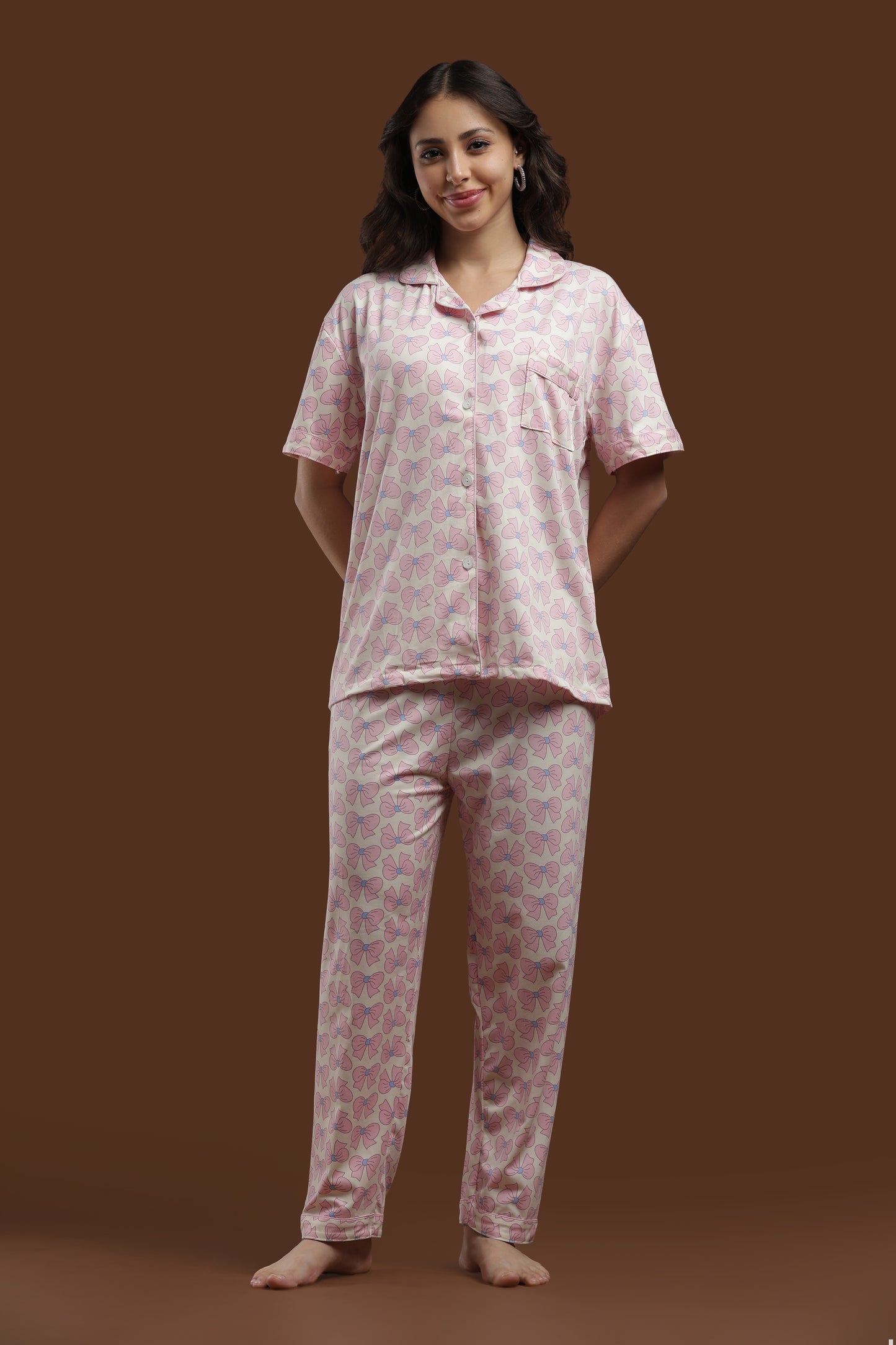 detailed view of the koozy pink ribbon pajama pants. highlighting the relaxed fit and the high-quality, repeating bow pattern on soft, off-white cotton fabric.