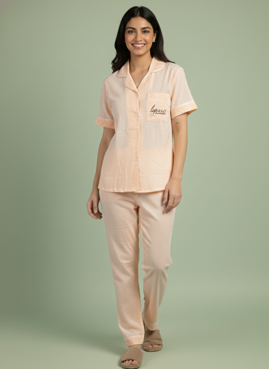 Effortlessly cute and comfortable Koozy Easy Breezy Peach pajama set. A Pinterest-style collared nightwear suite featuring a short-sleeve button-down top with chest pocket embroidery and matching long pants. Made from soft, breathable cloud cotton fabric for a light, easy, and cozy look.