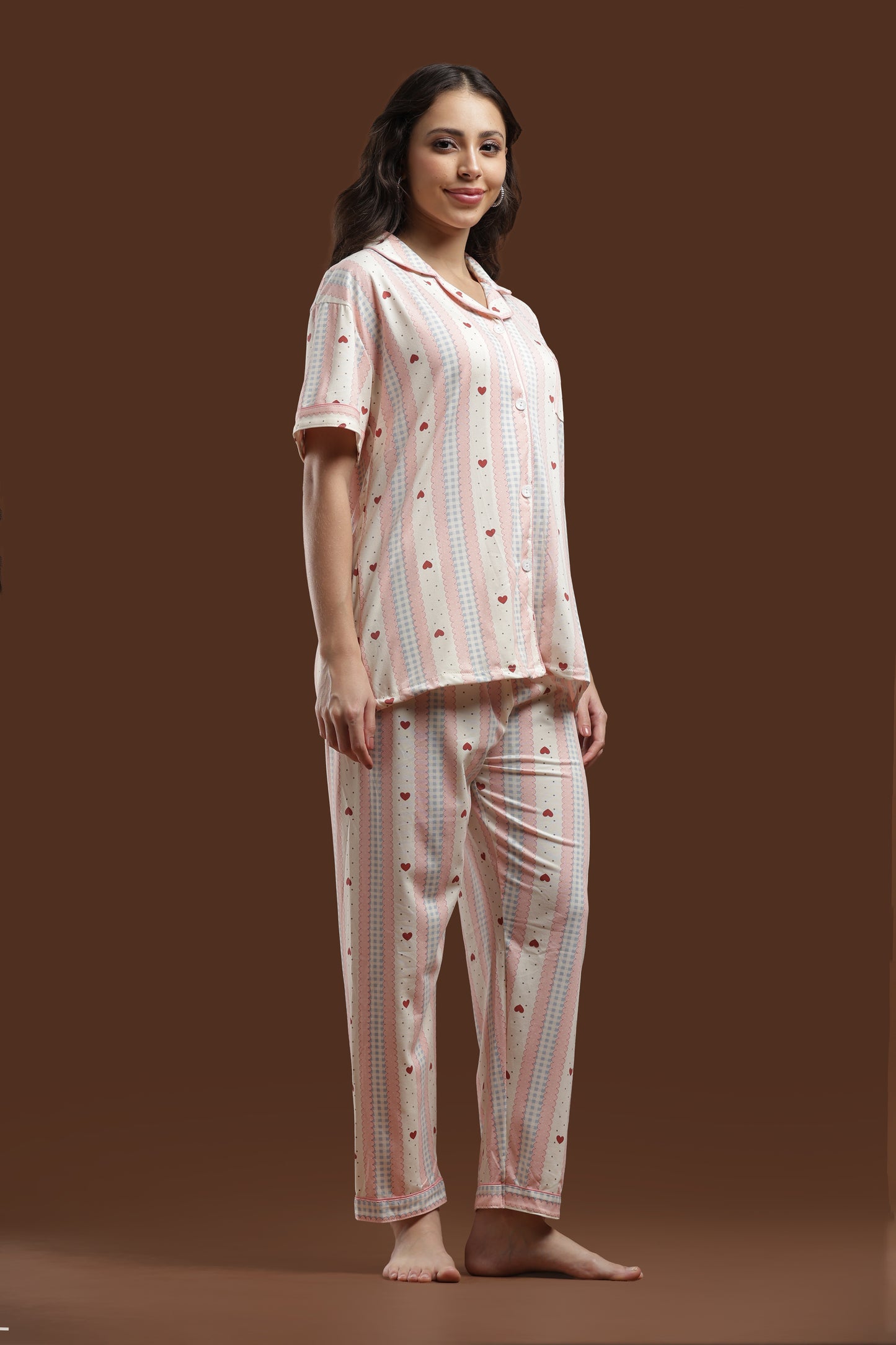 a woman posing in the koozy heart pj set , styled for a pinteresty morning vibe. highlights the cute, effortless look of the button-down top and matching pants.