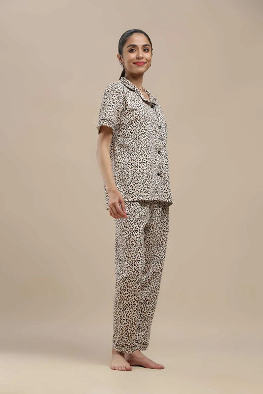 A complete view of the Koozy brown and black leopard print pajama set. This Pinterest-style cotton nightwear suite features a short-sleeve collared top and full-length pants, showcasing the striking animal pattern with dark button details. Designed for a softly structured, incredibly cozy, and fierce morning look.