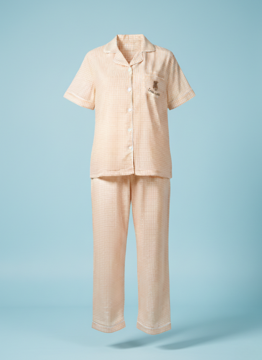 Ghost mannequin shot of the Koozy light peach checkered pajama set, showcasing the structured fit of the button-down short-sleeve shirt and matching long pants. This Pinterest-style cotton nightwear suite highlights the breathable fabric and relaxed silhouette for a soft, easy, and cozy look.