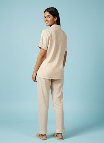 Full-length back view of the Koozy light peach PJ set for women, styled with matching neutral slides against a soft blue backdrop. This breathable cotton set offers a relaxed and inviting morning look.