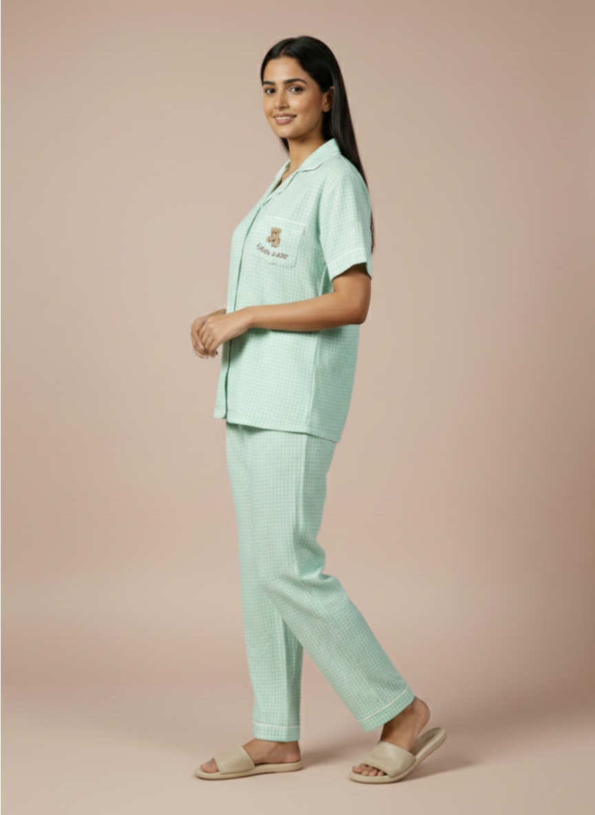a side view of the koozy light mint green checkered pajama set, showcasing the comfortable, airy drape of the button-down short-sleeve top and matching long pants.