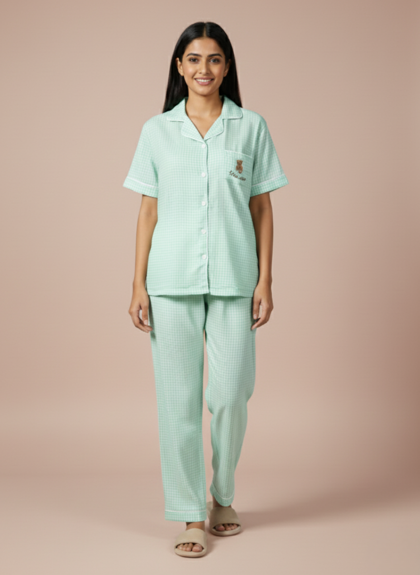 Light mint green Koozy nightwear suite featuring a cute bear emblem on the chest pocket. Highlights the soft, breathable cotton fabric and the delicate white pinstripe check pattern.